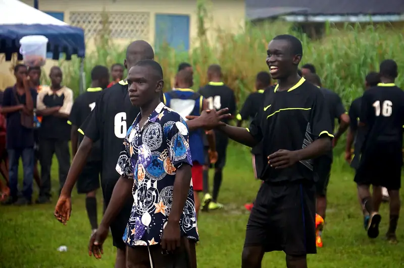 Players in black kit shaking hands and smiling after the game