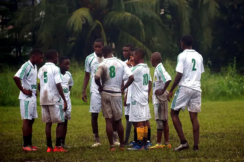 Players in muddy white kit gather in a huddle during a break in play