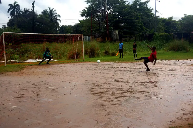 A player strikes a penalty as the goalkeeper crouches on the goal line
