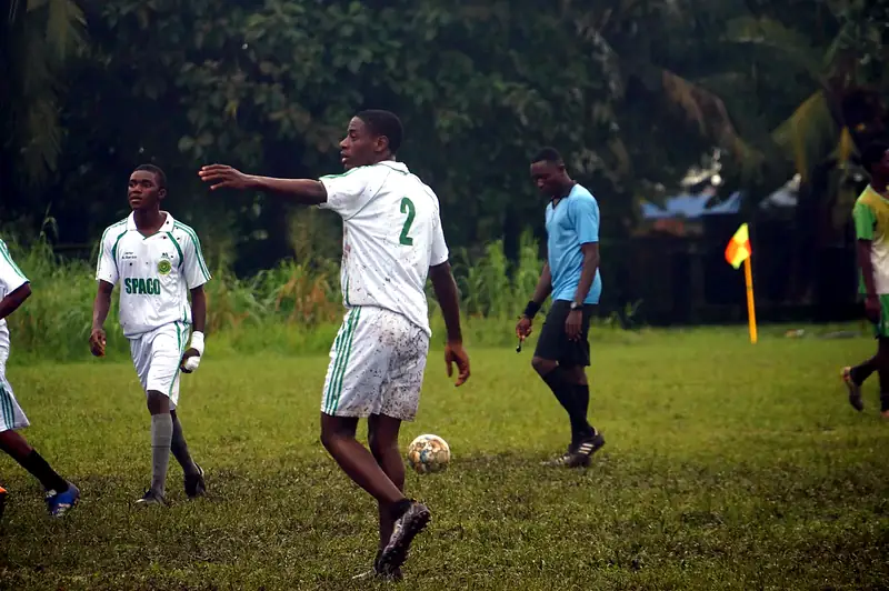 A player in white pointing instructions to teammates as the referee walks past