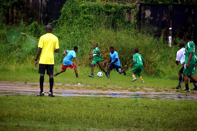 A referee in yellow watching a contest for the ball in the middle of the pitch