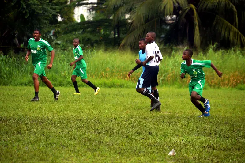 Players in green and light blue running upfield during a match