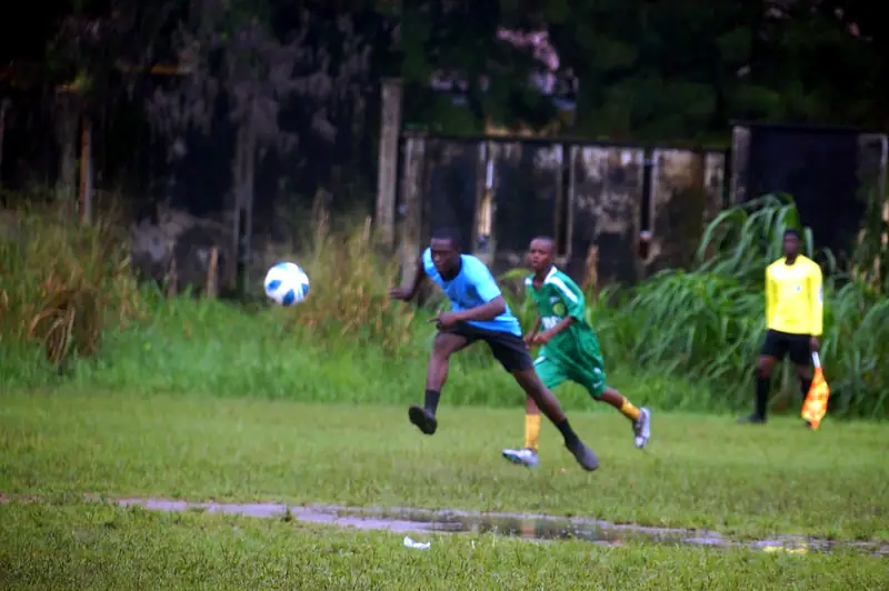 A player in light blue striking the ball as the linesman watches