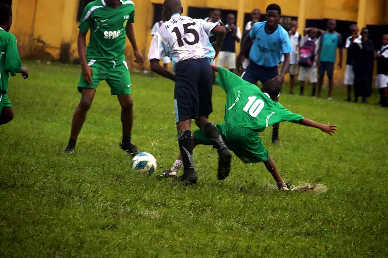 A player in green slides in to win the ball from an opponent in the rain