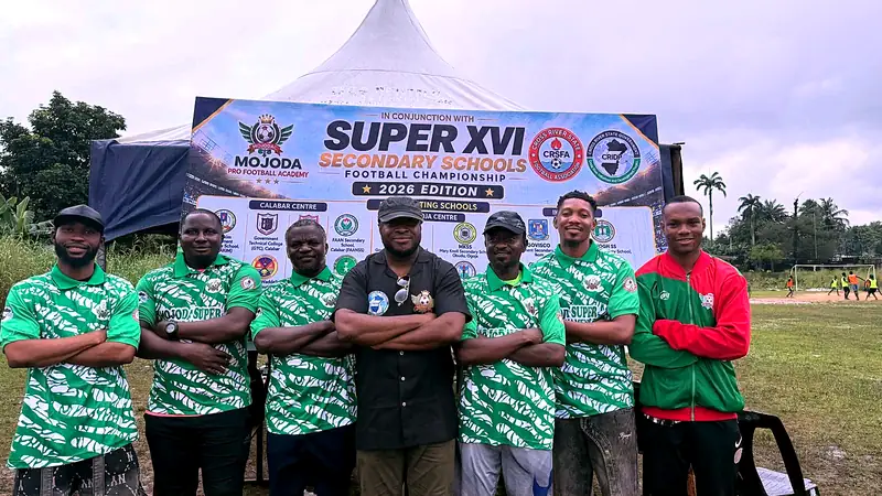 Seven organisers in matching green shirts posing arms-crossed in front of the Super XVI championship banner